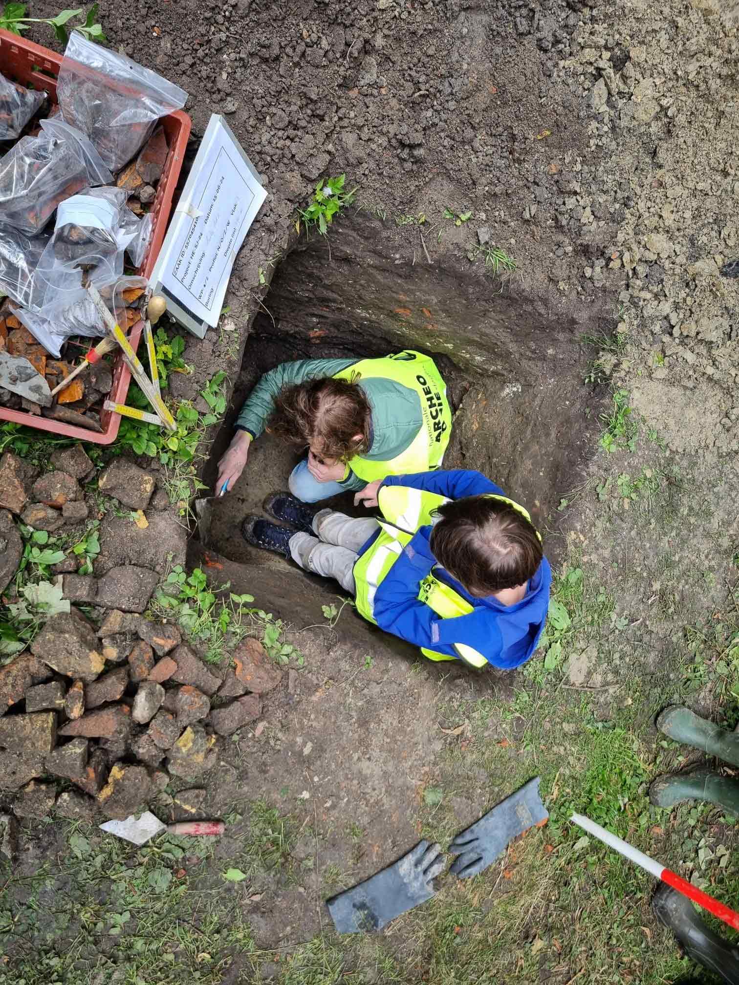 Twee jonge archeologen voor één dag onderzoeken scherven in een profielput.