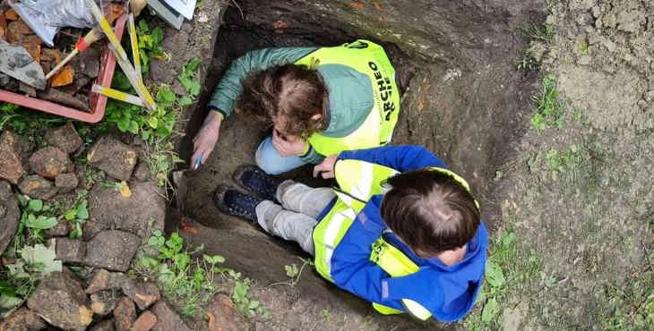 Twee jonge archeologen voor één dag onderzoeken scherven in een profielput.