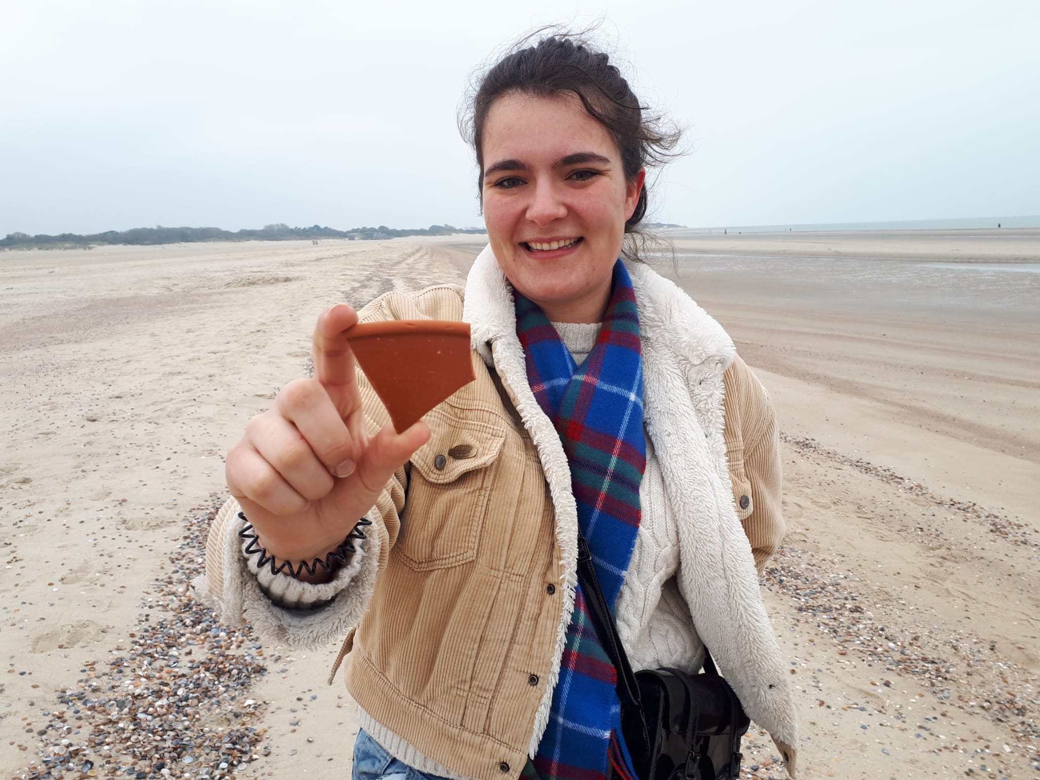 Een student van de UCR vindt een scherf op het Banjaardstrand (foto Marten Klop).