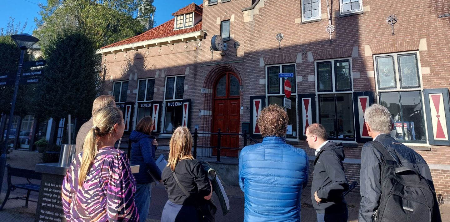 Betrokkenen bij het gemeentelijk planoverleg voor vergunningen bekijken de gevel van een museumpand.