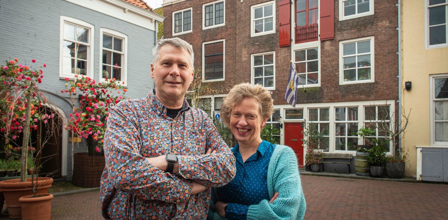 De trotse twee eigenaars van De Kaepstander poseren voor hun woning, aan de voet van de Lange Jan in Middelburg.