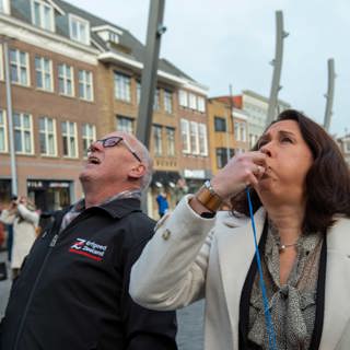Cultuurgedeputeerde Anita Pijpelink geeft op een fluitje het startsein voor het uitrollen van de banner, met naast haar teamleider Monumentenwacht Wim Jakobsen.