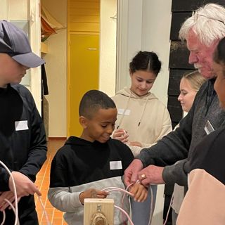 De rondleider van Museum Arnemuiden laat een groep kinderen zien hoe ze visnetten moeten knopen.