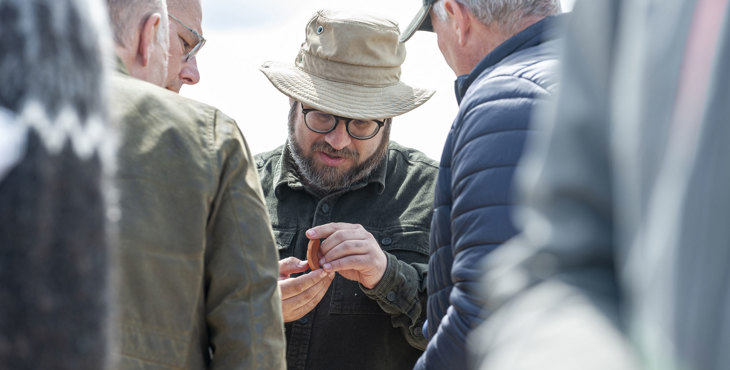 Een archeoloog onderzoekt een strandvondst van een strandzoeker.
