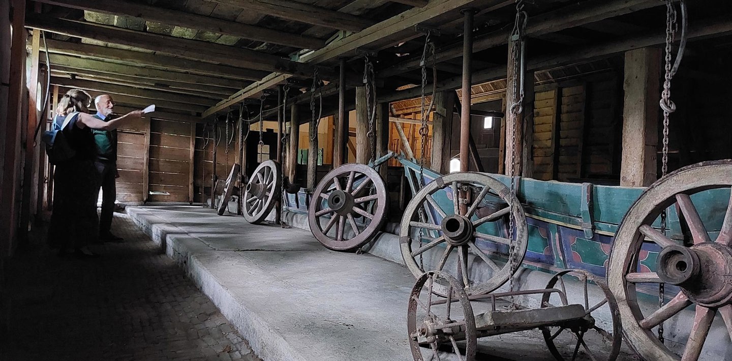 Twee mensen met elkaar in gesprek in een oude schuur met karrenwielen bij boerderij Zorgwijk in Ellewoutsdijk.