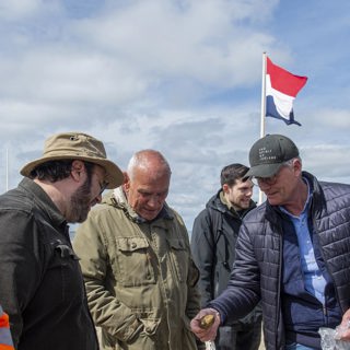 Strandzoekers tonen een strandvondst aan een archeoloog.