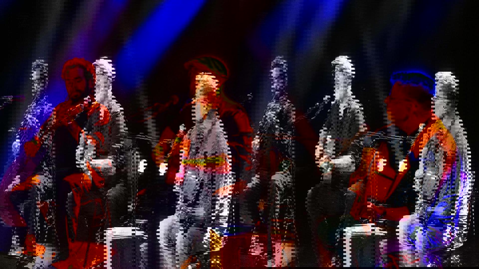 Een drietal mannen die op een podium muziek maken.