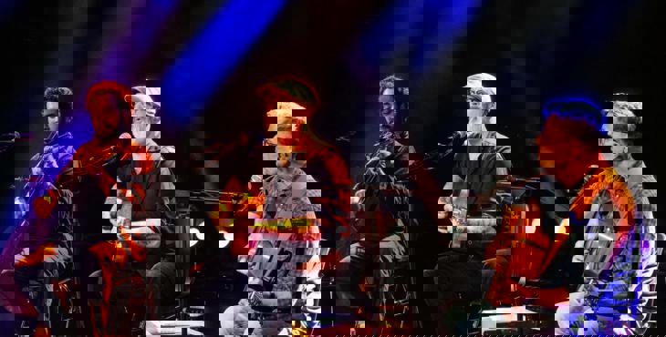 Een drietal mannen die op een podium muziek maken.